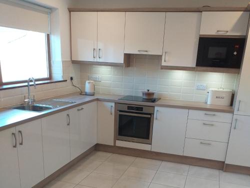 a kitchen with white cabinets and a sink at Holiday Home Behy Lodge Glenbeigh by Interhome in Behy Bridge