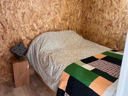 ein Schlafzimmer mit einem Bett mit einer Steppdecke darauf in der Unterkunft Logement près de la rivière in Athée