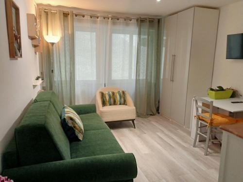 ein Wohnzimmer mit einer grünen Couch und einem Stuhl in der Unterkunft Central Plaza Cozy Studio accesso diretto alle piste in Sauze d'Oulx