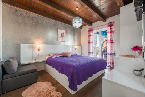 a bedroom with a purple bed and a chair at Stone villa Jurenda with pool in Debeljak