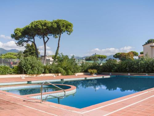 a swimming pool with trees and a mountain in the background at Apartment Appartamento Residence Henderson by Interhome in Cinquale