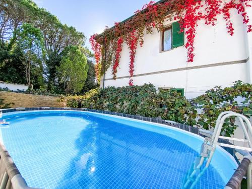 a swimming pool in front of a building with red flowers at Holiday Home La Pausa by Interhome in Ponteginori