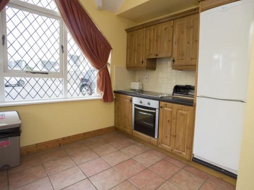 a kitchen with wooden cabinets and a white refrigerator at Holiday Home Willow Grove HC No- 4 by Interhome in Mervyn