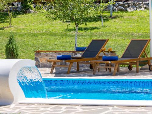 a pool with two chairs and a table next to a swimming pool at Holiday Home Relax Lika by Interhome in Tomingaj