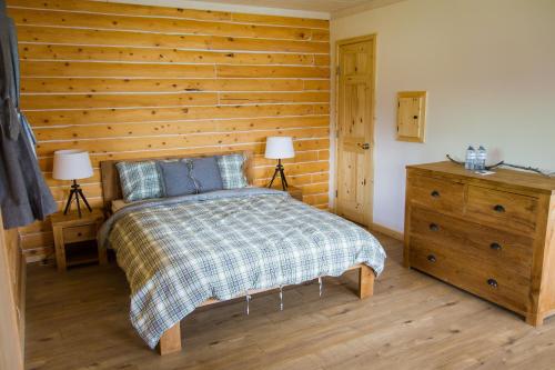 1 dormitorio con 1 cama y pared de madera en Southern Lakes Resort en Tagish