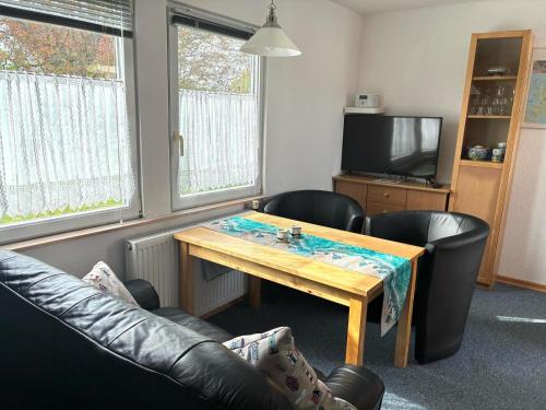 a living room with a table and leather chairs at Ferienhäuser Vogelsang in Sagard