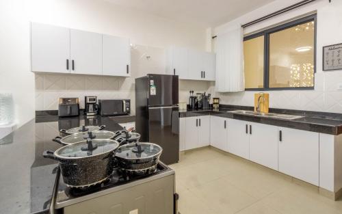 a kitchen with three sinks and white cabinets at Elna's Baobab Waves - 2BR and 3BR Beachfront Nyali in Mombasa