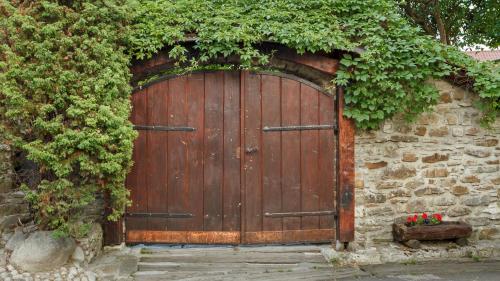 a wooden gate in a stone wall with flowers at Penzion Barborka in Poprad
