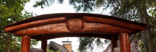 a wooden bench with an archway in a park at Penzion Barborka in Poprad