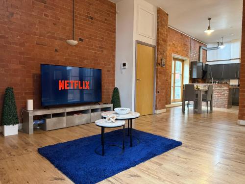 a living room with a tv and a blue rug at City Centre 2-Bed, 2 Balconies, 65 Inch TV, Free Parking, Coffee Machine, Netflix in Leicester