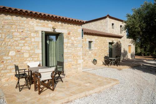 eine Terrasse mit Tisch und Stühlen vor einem Gebäude in der Unterkunft Olive Coast Houses in Kyparissia