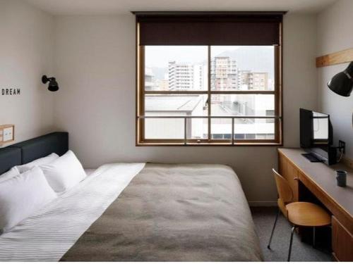 a bedroom with a bed and a desk and a window at Hotel Relief Kokura Annex in Kitakyushu