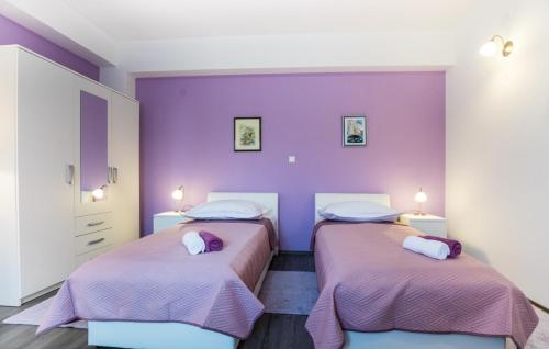 2 Betten in einem Zimmer mit lila Wänden in der Unterkunft Holiday home Ostojic by Villas Guide in Peračko Blato