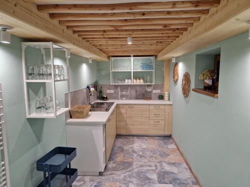 Una cocina con encimeras blancas y techos de madera. en Apartmány KOUTY 23, en Kouty