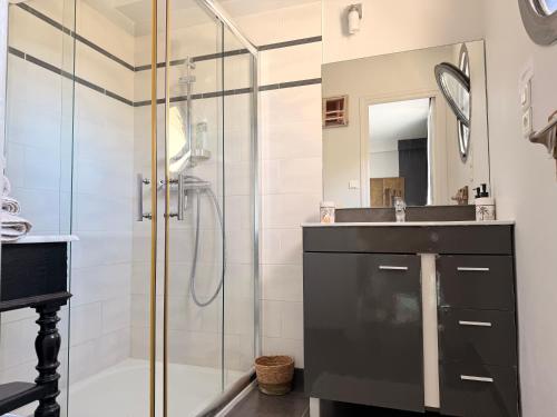 Un baño con ducha de cristal y lavabo. en Villa du Siéck bord de mer piscine 14 P, en Santec