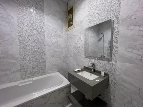 a white bathroom with a tub and a sink and a bath tub at بوتيك هاوس بدخول ذاتي وصالة أنيقة in Hail