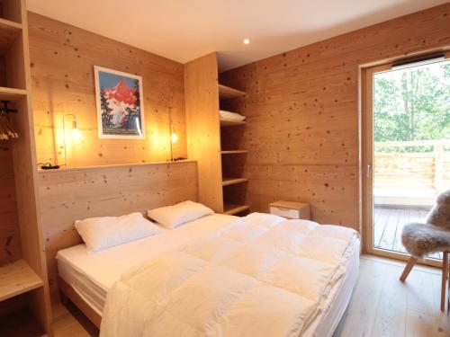 a bedroom with a large bed in a wooden wall at Appartement ski aux pieds, 3 pièces, 6 pers, terrasse sud, près des Carroz - FR-1-572-248 in Les Carroz d'Araches