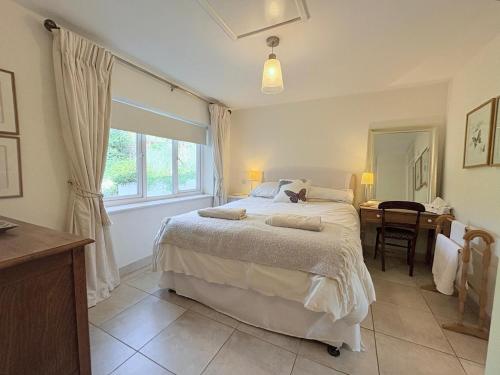 a bedroom with a bed and a desk and a window at Spring Grange Cottage in Winscombe