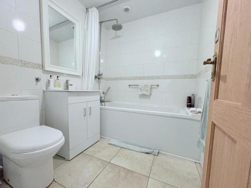 a bathroom with a toilet and a tub and a sink at Spring Grange Cottage in Winscombe