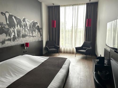 a bedroom with a bed and two chairs and a television at Bastion Hotel Almere in Almere