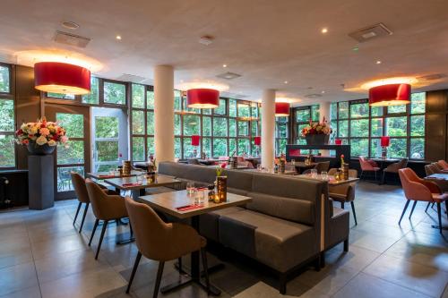 a restaurant with tables and chairs and windows at Bastion Hotel Amsterdam Zuidwest in Amsterdam