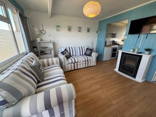 een woonkamer met twee banken en een open haard bij 46 Hectors, Sunbeach, Scratby - Two bed chalet, sleeps 4, pet friendly, free Wi-Fi, free entry to onsite clubhouse and bed linen and towels included in Great Yarmouth