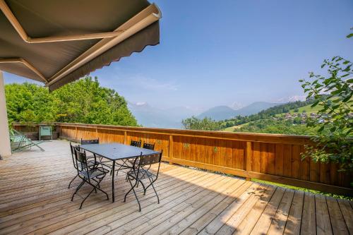 un patio con mesa y sillas en una terraza de madera en Appartements dans le Chalet Nessa - Combloux, en Combloux