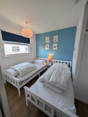 two beds in a bedroom with a blue wall at Hectors, Two bed Chalet on Sunbeach Holiday Park - Sleeps 4, pet friendly - plus WiFi, bed linen and towels included only 300m from the beach! in Great Yarmouth