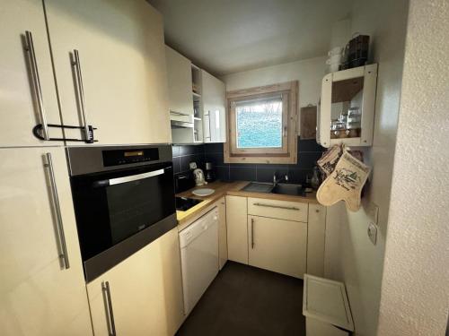 eine kleine Küche mit weißen Schränken und einem Fenster in der Unterkunft Spacieux 2 Pièces aux Carroz, 6 Pers., Balcon ensoleillé - FR-1-572-9 in Arâches-la-Frasse