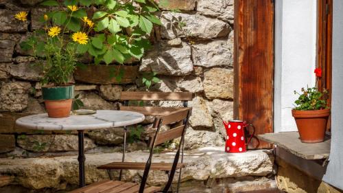 a table and a chair with flowers on a stone wall at Penzion Barborka in Poprad