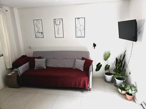 a living room with a bed with a red blanket at Quarto Privado com Suíte - Oktoberfest 10min in Blumenau