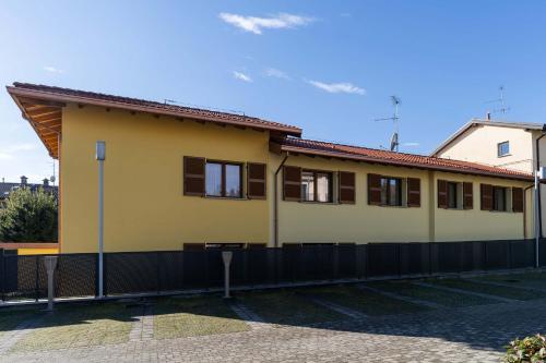 a yellow house with a black fence in front of it at Bilocale Gelsomino - Cascina Da Rosa in Capiago Intimiano