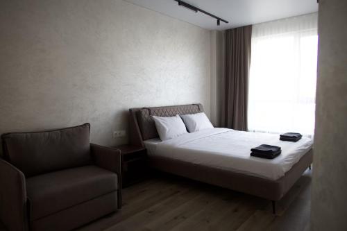 a bedroom with a bed and a chair and a window at Pysanka apartments in Kolomiya