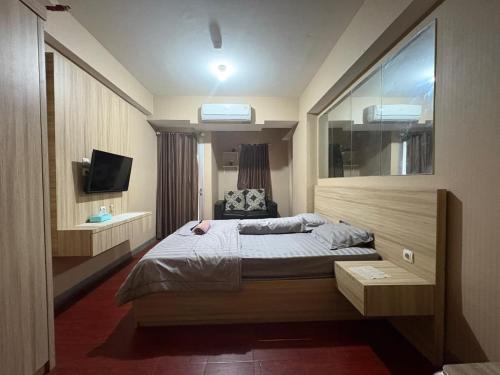 a hotel room with a bed and a television at Apartemen Gunung Putri by Maknyoss Rooms in Pabuaran Satu