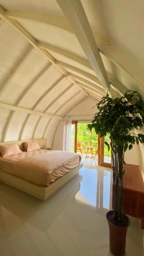 a bedroom with a bed and a potted plant at Mimpi Manis Villas in Tetebatu