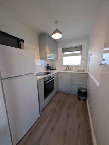a kitchen with a white refrigerator and a wooden floor at 319, Two bed newly refurbished chalet on Sund0wner Holiday Park - Sleeps 5, pet friendly - Includes electricity, bed linen and towels - Entertainment options close by in Hemsby