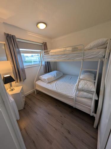 a bedroom with two bunk beds and a lamp at 319, Two bed newly refurbished chalet on Sund0wner Holiday Park - Sleeps 5, pet friendly - Includes electricity, bed linen and towels - Entertainment options close by in Hemsby