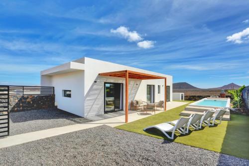 a modern house with a swimming pool and lawn at ISLAND WEEK Fuerteventura in La Oliva