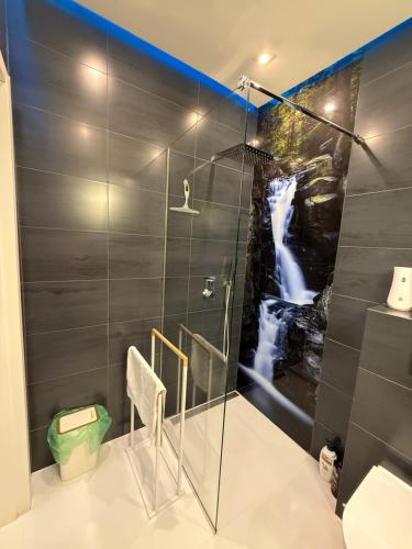 a bathroom with a shower with a painting of a waterfall at Komfort House apartament z tarasem in Ełk