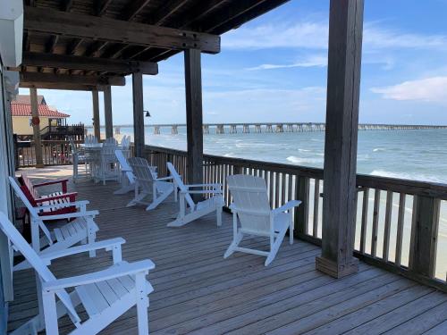 a deck with white chairs and the ocean and a pier at Atlantis - Oceanfront Seating at its Finest! in Freeport
