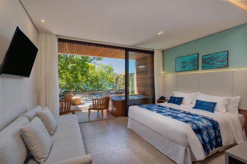a bedroom with a large bed and a living room at Casa Di Sirena Ilhabela in Ilhabela