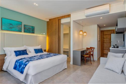 a bedroom with a bed and a desk and a kitchen at Wyndham Ilhabela Casa Di Sirena in Ilhabela