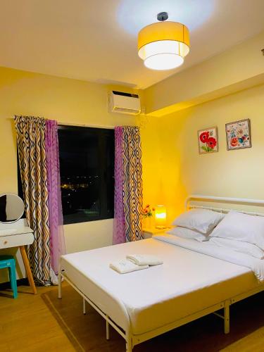 a bedroom with a white bed and a window at Angsana Breeze at Paseo Verde Las Piñas in Manila