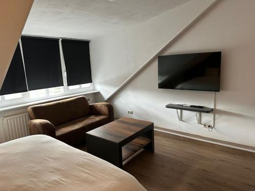 a bedroom with a bed and a couch and a tv at B&B Santorini Maasbree in Maasbree