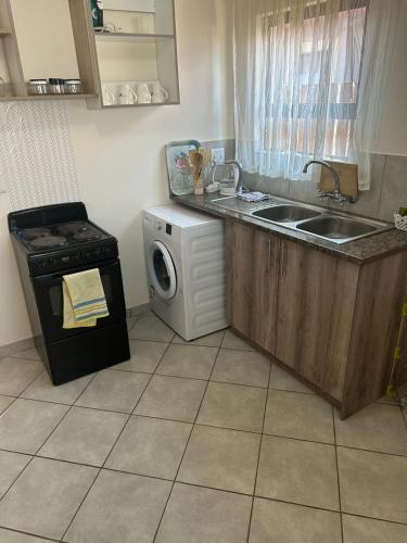 a kitchen with a sink and a washing machine at MV self-catering Linden in Bloemfontein