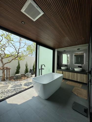 a bathroom with a large white tub in front of windows at 913 Luxury Pool Villa Khaolak in Khao Lak