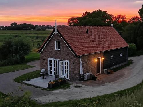 a small brick house with a sunset in the background at Appartement Het Brummelhof in Vrouwenpolder