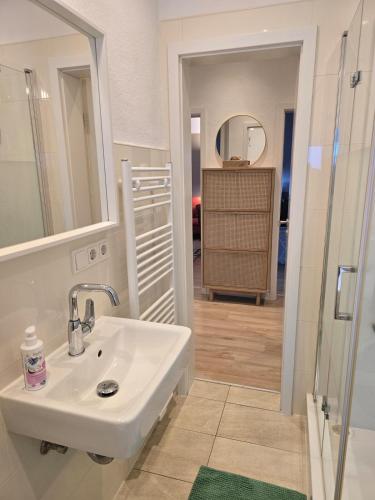 ein weißes Badezimmer mit Waschbecken und Spiegel in der Unterkunft Modern Köln Flat 20mins Messe 25mins Neumarkt in Köln