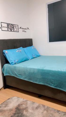 a bed with blue pillows and a flat screen tv at Residência da day in Aracaju