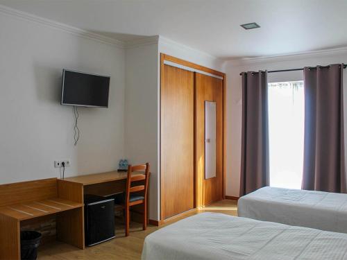 a hotel room with a desk and a television on the wall at AL Novavista by BPX in Madalena